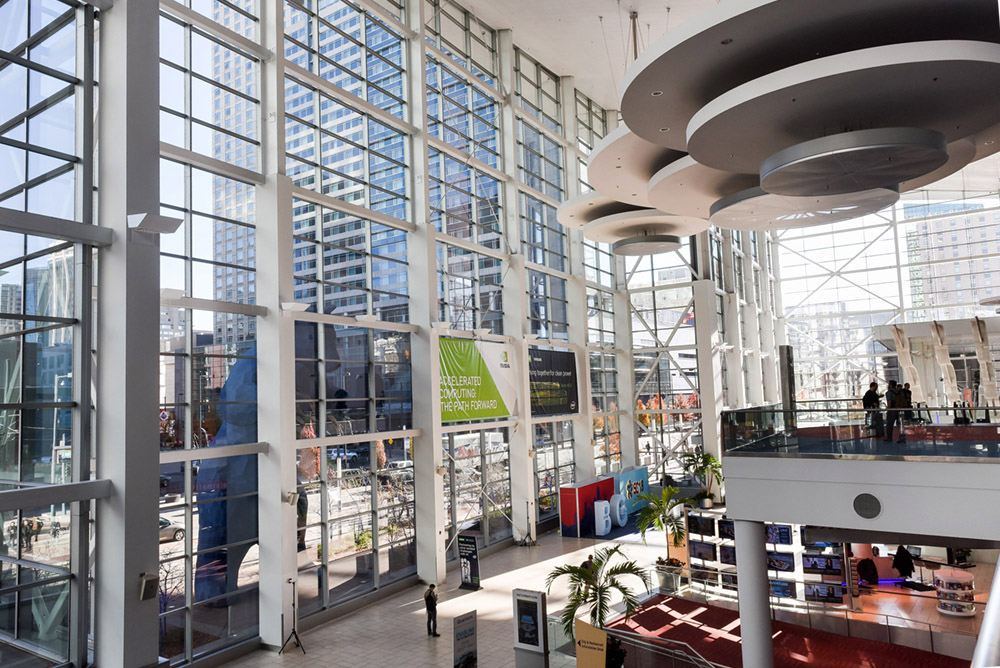 Entrance to event building with large glass walls, and large circular fixtures.